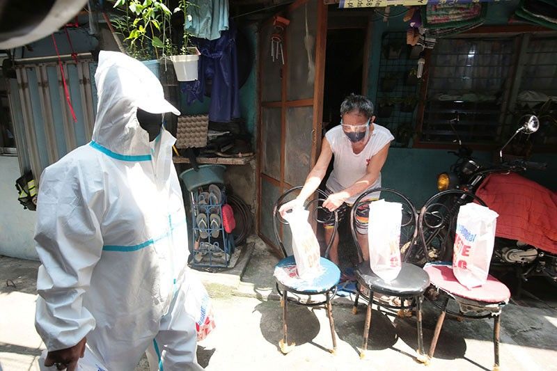 Residents in a compound in Brgy. Pinyahan, Quezon City which was placed under special concern lockdown due to COVID-19 cases receive food aid on Sept. 15, 2021. (Photo / Retrieved from Philstar)